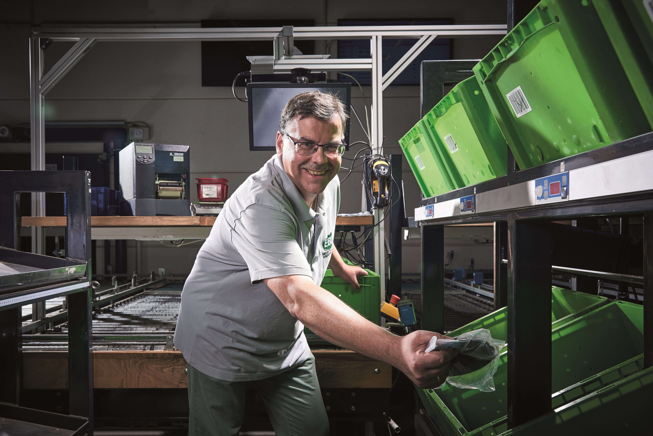 Worker sorts green bins in warehouse.